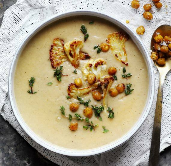 Schale mit Suppe, daneben Löffel und Kichererbsen