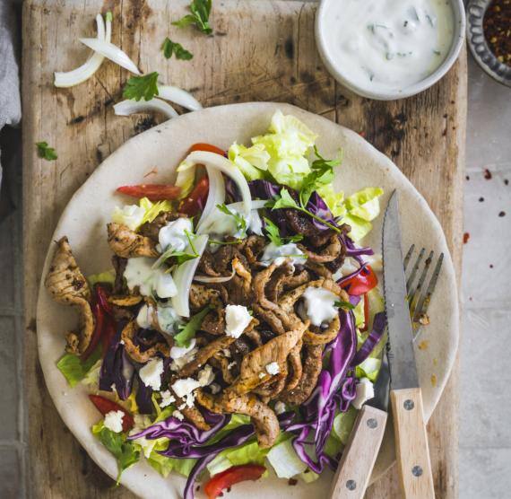 Teller mit Fleisch und Salat auf Holzbrett