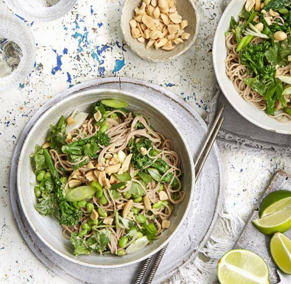 Schalen mit Asia-Nudeln, Stäbchen, Erdnüssen und Limetten