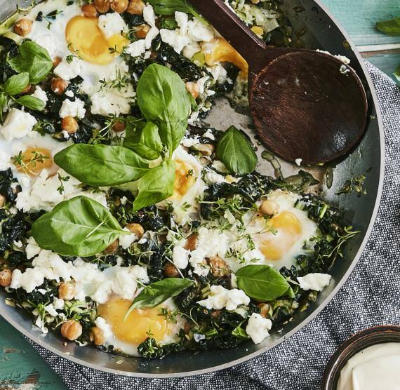 Eisenpfanne mit Shakshuka, Basilikum und Eiern.