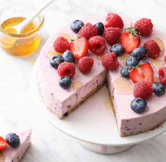 Torte mit Beeren und Schale mit Honig