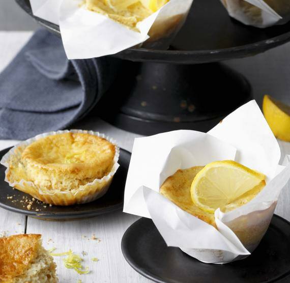 Zitronen-Muffins in Backpapier auf schwarzen Tellern