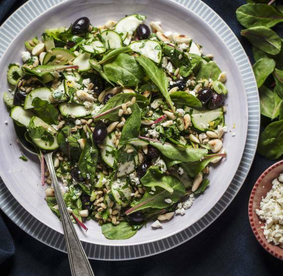 Teller mit Spinat, Mangold, Zucchini, Oliven, Feta und Kernen