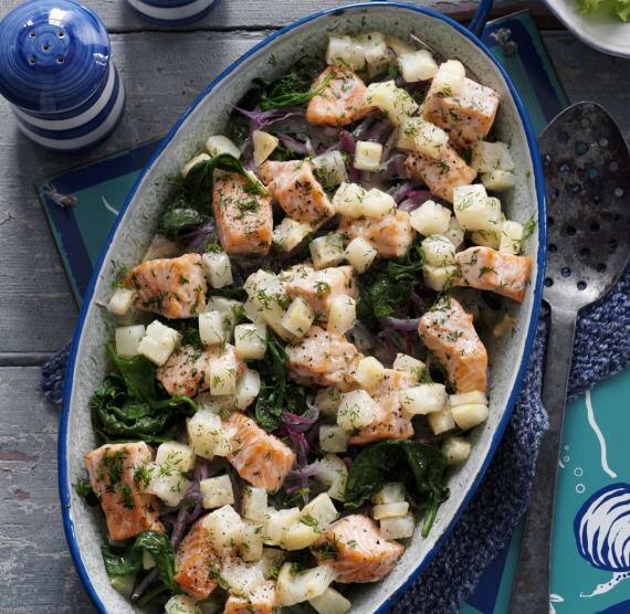 Auflaufform mit Lachs- und Selleriewürfeln auf Spinatbett mit roten Zwiebeln