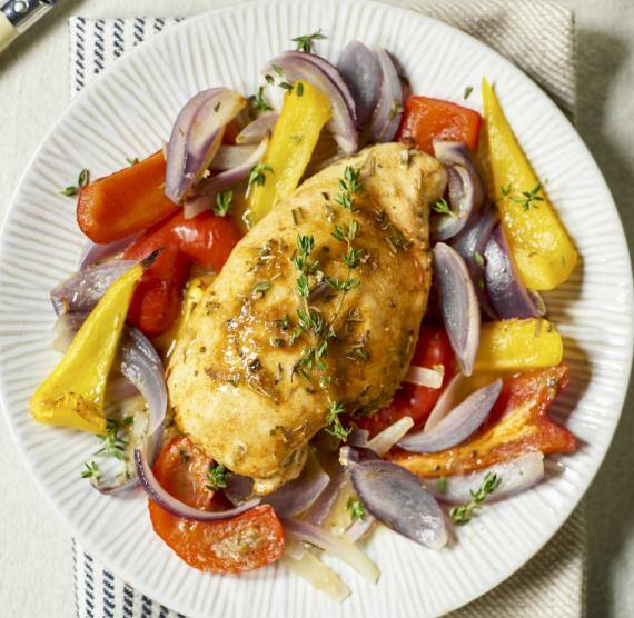 Heller Teller mit Hähnchenbrustfilet auf Paprika