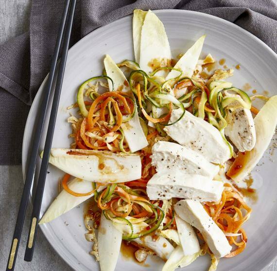 Hähnchenstücke auf Gemüsebett auf einem weißen Teller