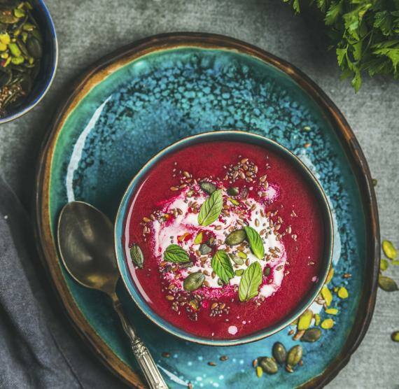 Schüssel mit Rote Bete-Suppe, Sojajoghurt, Saaten und Kernen und Minzblättern