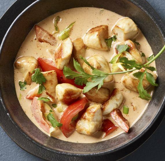 Curry in einer dunklen Schüssel mit frischem Koriander und Löffel