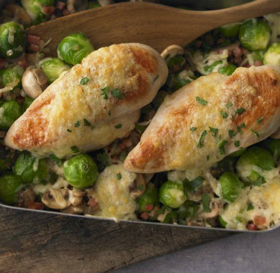 Bräter auf Brett mit Rosenkohl und Hähnchenbrust überbacken mit Käse