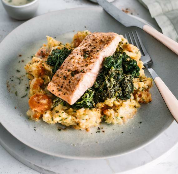 Teller mit Püree, Spinat und Lachs mit Messer und Gabel