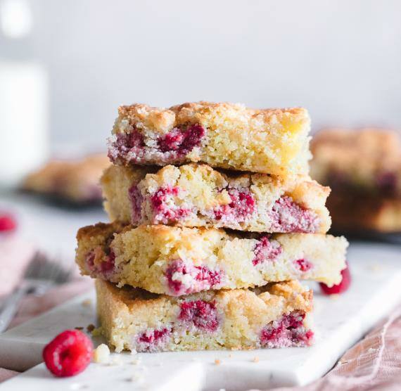 Kuchen gestapelt auf einem Brett, rosa Tuch und Kanne mit Milch