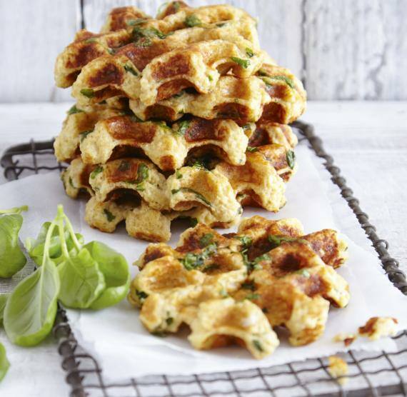 Low Carb-Waffeln gestapelt auf einem Gitter, daneben Basilikum