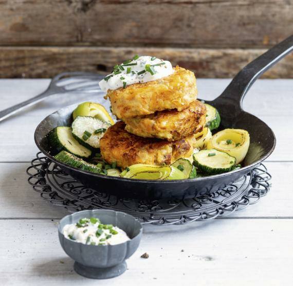 Kürbisbratlinge gestapelt in Pfanne mit Dip und Lauch