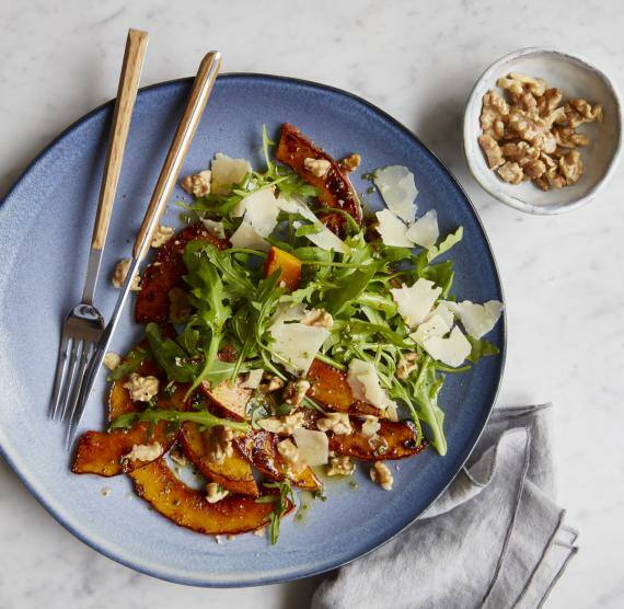 Blauer Telle mit Salat und Kürbis, daneben Walnusskerne