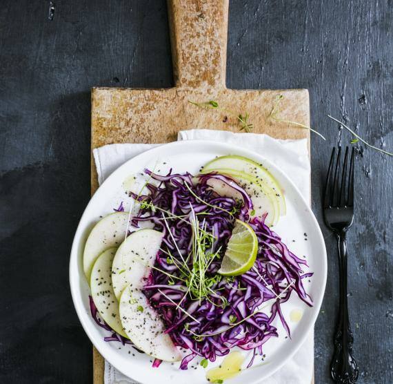 Teller auf Brett mit Rotkohlsalat, Birne, Kresse und Limette
