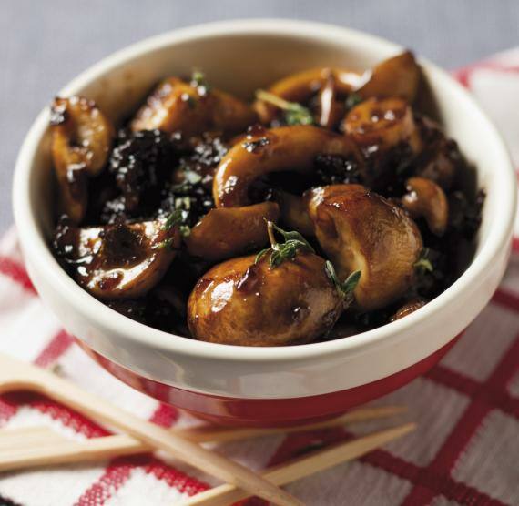 Schüssel mit glasierten Chahmpignons, darüber Thymian