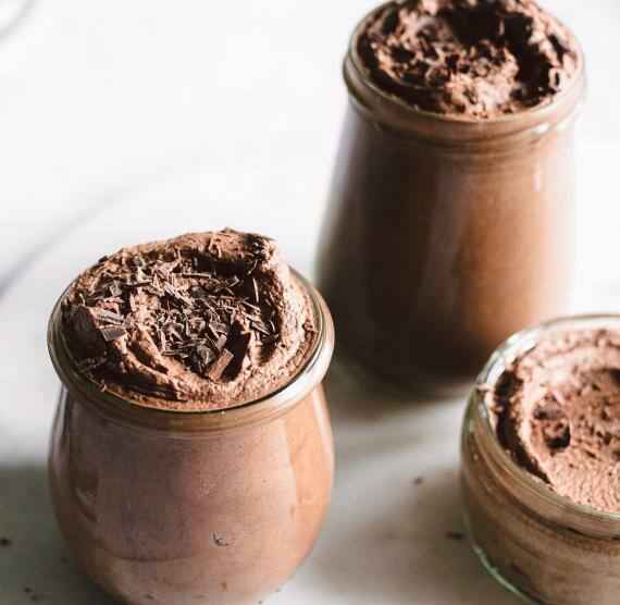 Dessert in Gläsern auf einer Platte, Löffel liegen daneben