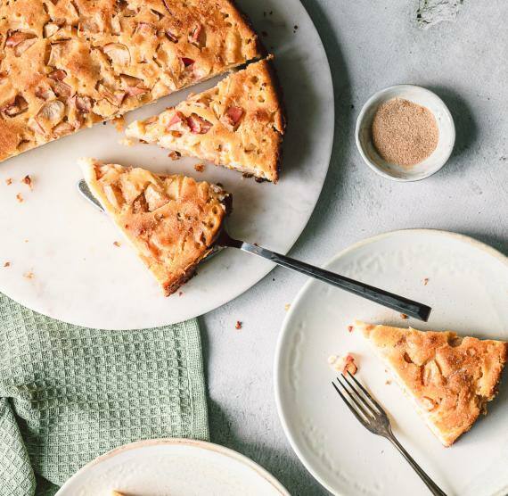 Apfelkuchen auf einer Servierplatte, Teller mit Kuchenstücken daneben