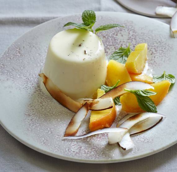 Puddingtörtchen auf einem Teller mit Pfirsichspalten und Minzblättern