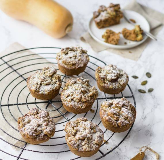 Rundes Gitter mit Kürbimuffins, darüber Puderzucker