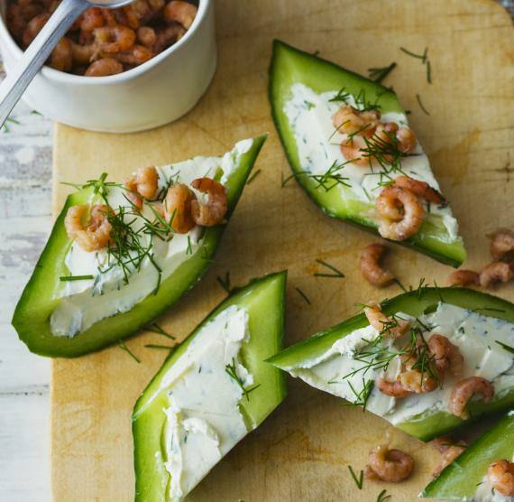 Gurken-Happen auf einem Holzbrett mit Nordseekrabben in einer kleine Tasse