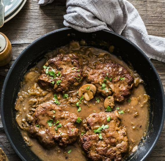 Pfanne mit Frikadellen und Pilzen auf Holzhintergrund