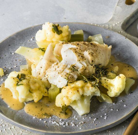 Teller Mit Blumenkohl, Fisch und Sauce auf Brett mit Besteck