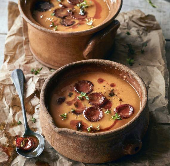 Zwei Tonschalen auf Backpapier mit Kürbissuppe