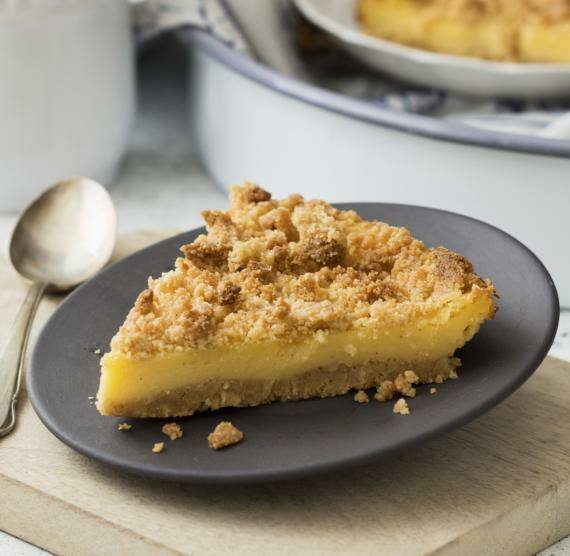 Stück Pudding-Tarte auf einem dunklen Teller, gedeckter Tisch