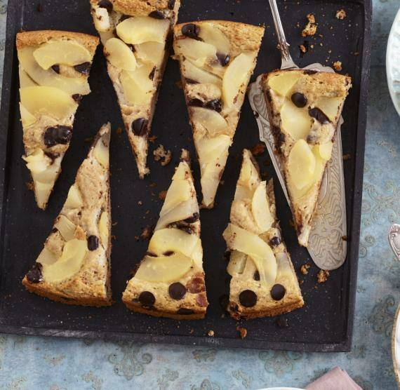 Birnenkuchen in Stücke geschnitten auf einem Blech und auf drei Tellern