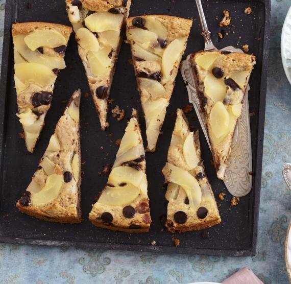 Birnenkuchen in Stücke geschnitten auf einem Blech und auf drei Tellern