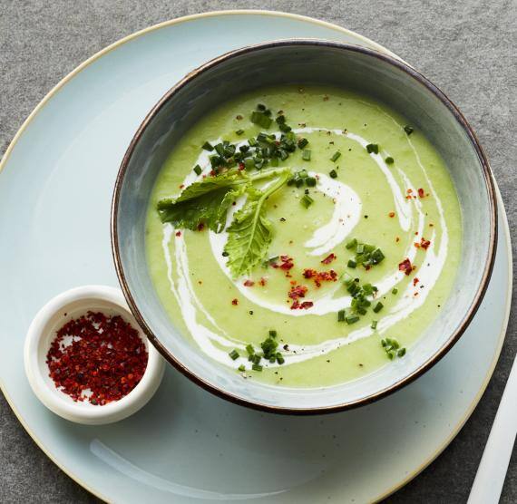 Suppe in einer Schale angerichtet auf eiem Teller mit Chili und Löffel