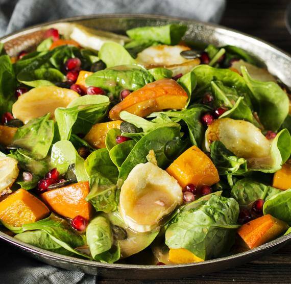 Salat mit Kürbis, Ziegenkäse und Granatapfel auf Teller