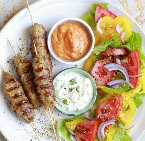Teller mit Cevapcici, Salat und jeweils Schälchen mit Ajvar und Tzaziki