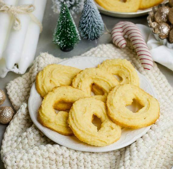 Teller mit Spritzgebäck auf Tisch mit Weihnachtsdeko