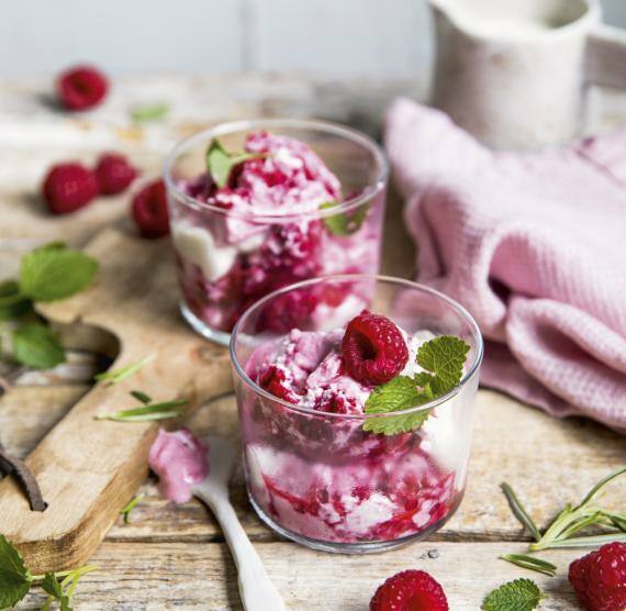 Zwei Gläser mit Himbeer-Frozen-Yogurt, darüber frische Himbeeren und Minze