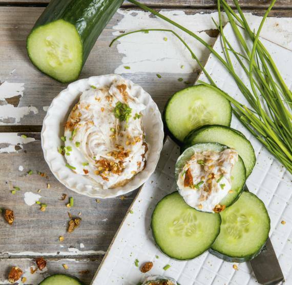 Brett mit Grukenscheiben und Schälchen mit Créme fraîche-Dip, daneben Schnittlauch