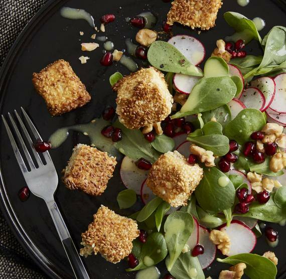 Teller mit Portulak, Radieschenscheiben, Granatapfelkernen und panierten Tofuwürfeln