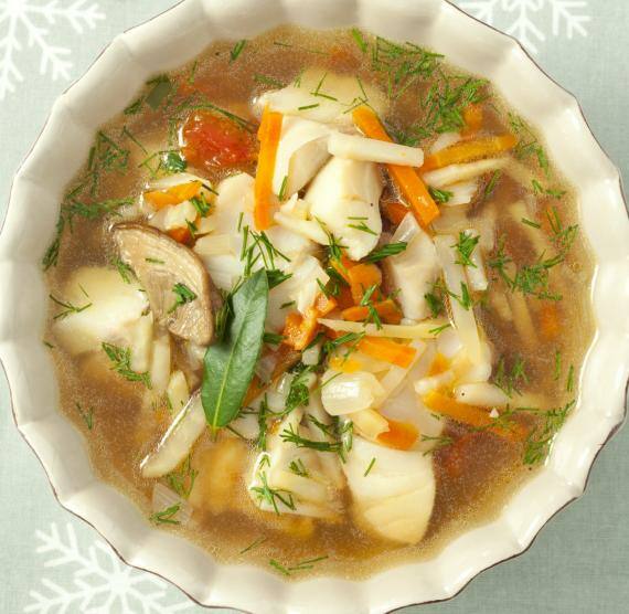 Klare Suppe mit Fisch und Gemüse in einer Schale