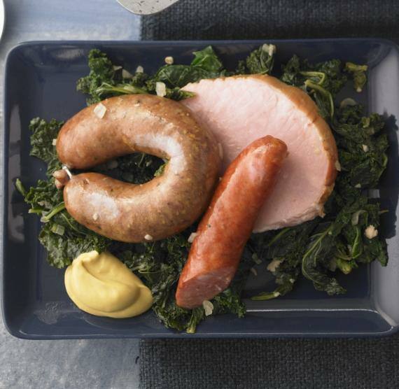 Topf und Teller mit Grünkohl, Kassler, Speck und Würstchen