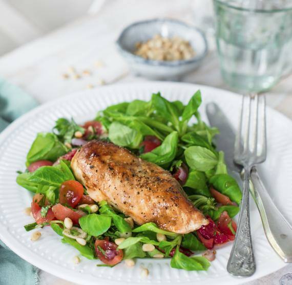 Salat mit Tomaten und Hähnchen auf Teller mit Wasser