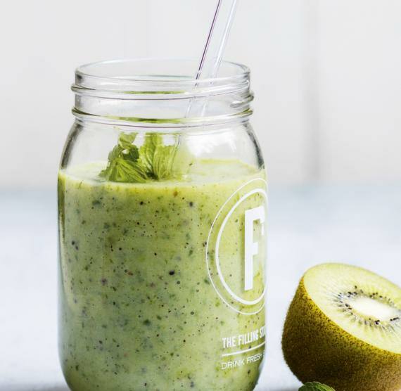 Glas mit Kiwi-Shake mit Strohalm, Minze und Kiwi