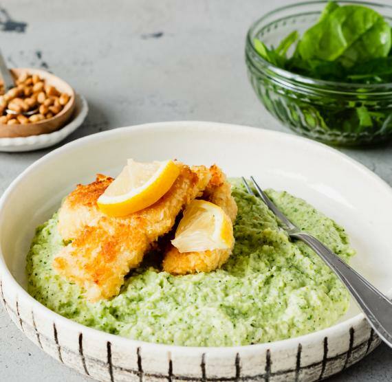 Fischstäbchen und Püree auf Teller und Spinatsalat in Schale
