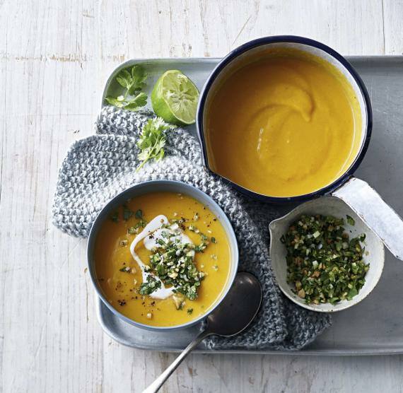 Schüsseln mit Kürbissuppe, daneben Schälchen mit Toppings