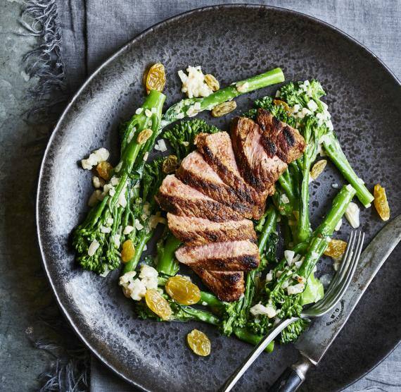 2 Teller mit geschnittenem Fleisch, dazu Brokkolini, Sultaninen und helle Sauce
