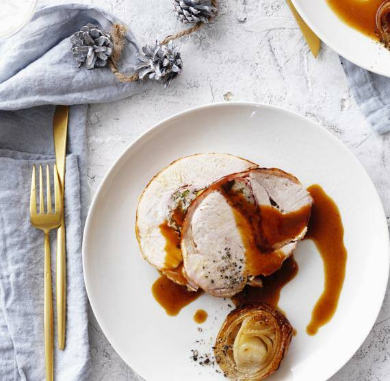 Putenroulade auf weißen Tellern, dazu glasierte Zwiebelringe
