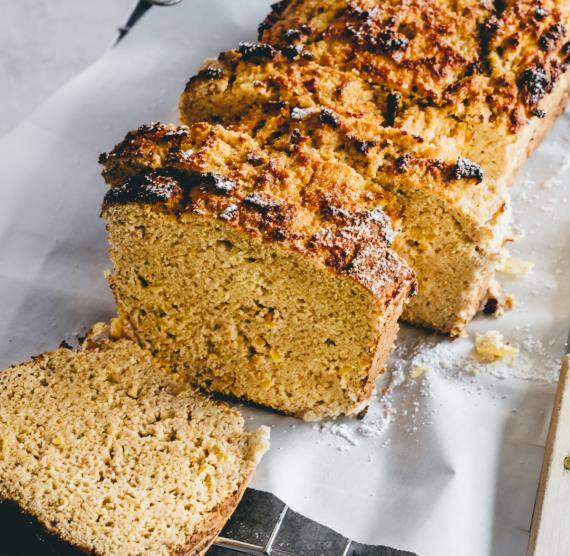 Angeschnittenes orangenes Brot auf weißem Papier, daneben großes Schneidemesser