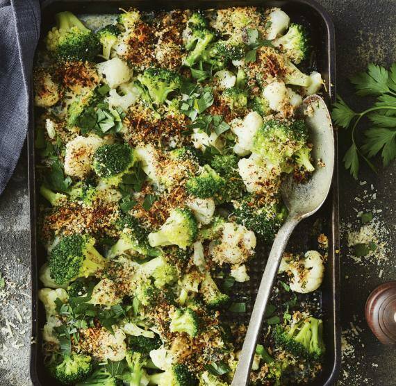 Brokkoli- und Blumenkohlröschen in Auflaufform, darüber gemahlene Haselnuss und Parmesan