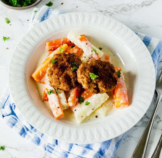 Teller mit Gemüsestiften mit Rahm, darauf Frikadellen, daneben Schälchen mit Petersilie