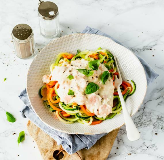 Gemüse-Spaghetti mit Lachs-Fetasauce, darüber Basilikum